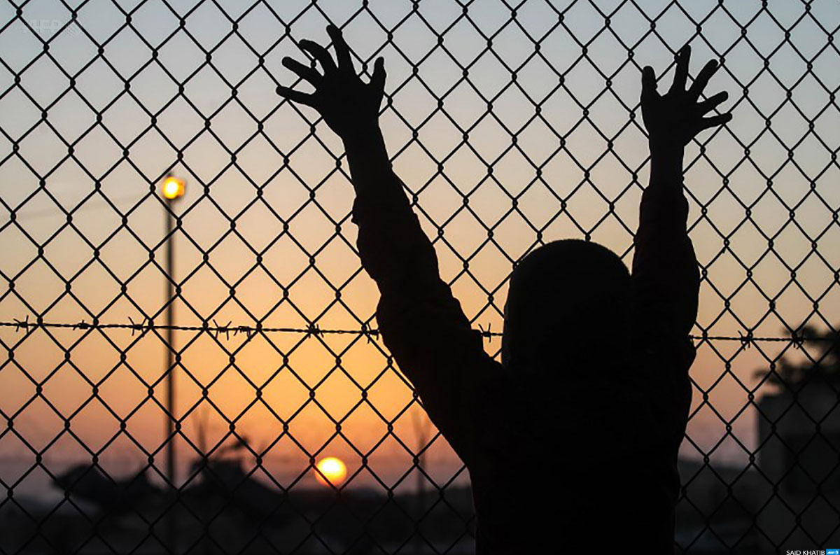 child-holding-hands-against-fence