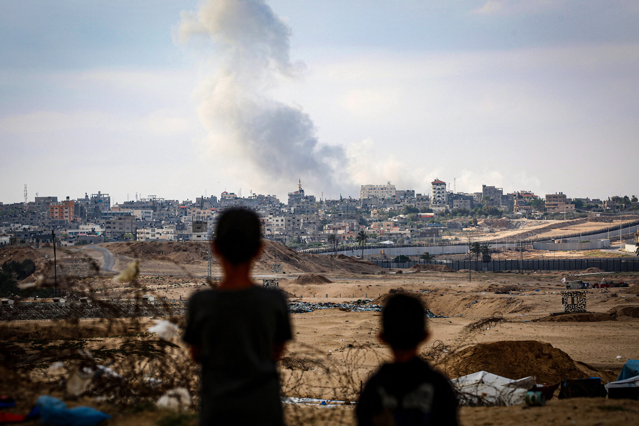 TOPSHOT-PALESTINIAN-ISRAEL-CONFLICT TOPSHOT - Boys watch smoke billowing during Israeli strikes east of Rafah in the southern Gaza Strip on May 13, 2024, amid the ongoing conflict between Israel and the Palestinian militant group Hamas. (Photo by AFP) (Photo by -/AFP via Getty Images)