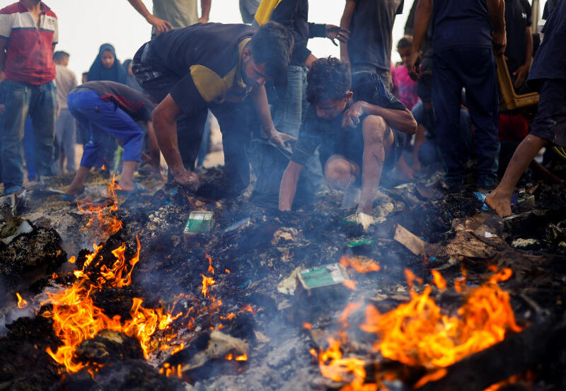 Palestinians search for food among burnt debris in the aftermath of an Israeli strike on an area designated for displaced people, in Rafah in the southern Gaza Strip, May 27, 2024. REUTERS/Mohammed Salem