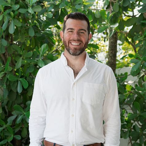 OIP-811838568 A man in a white shirt smiles for a photo.