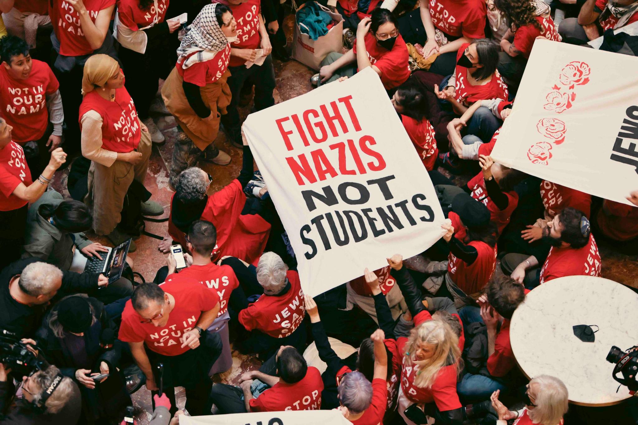 A group of people hold a banner reading "Fight Nazis, not students".